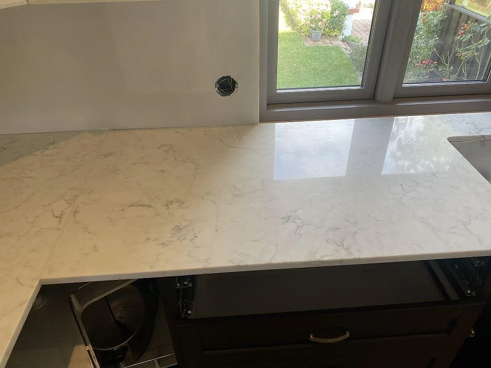 Vit Technistone Mystery White köksbänkskiva, polerad, med grå ådring längs en bänkrad vid fönstret i Ystad.
