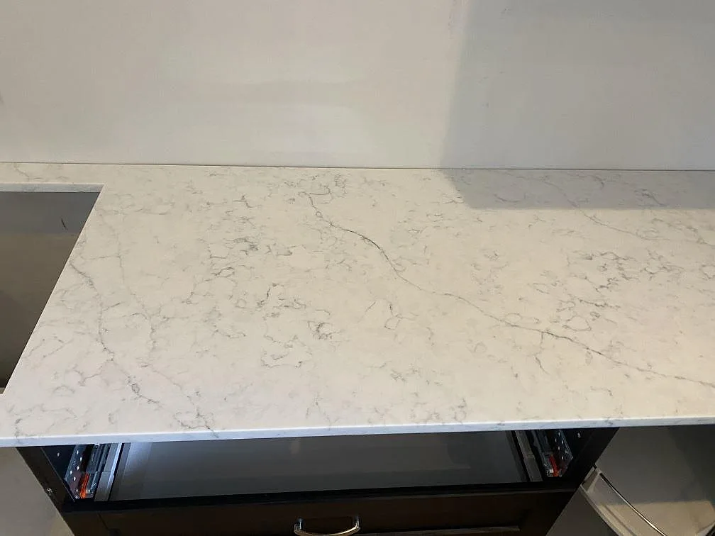 Köksbänkskiva i vit Technistone Mystery White med mjuk grå ådring i ett kök under montering i Ystad.