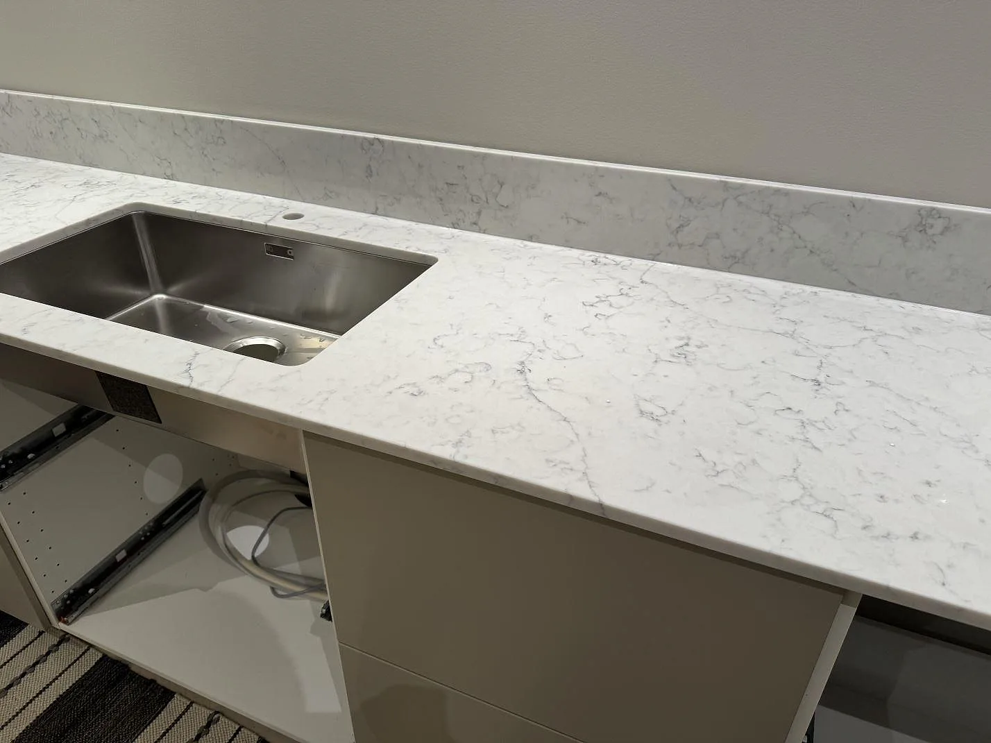Polerad köksbänkskiva i Technistone Mystery White med rostfri diskho, blandarhål och låg stänkkant i ett kök i Ystad.