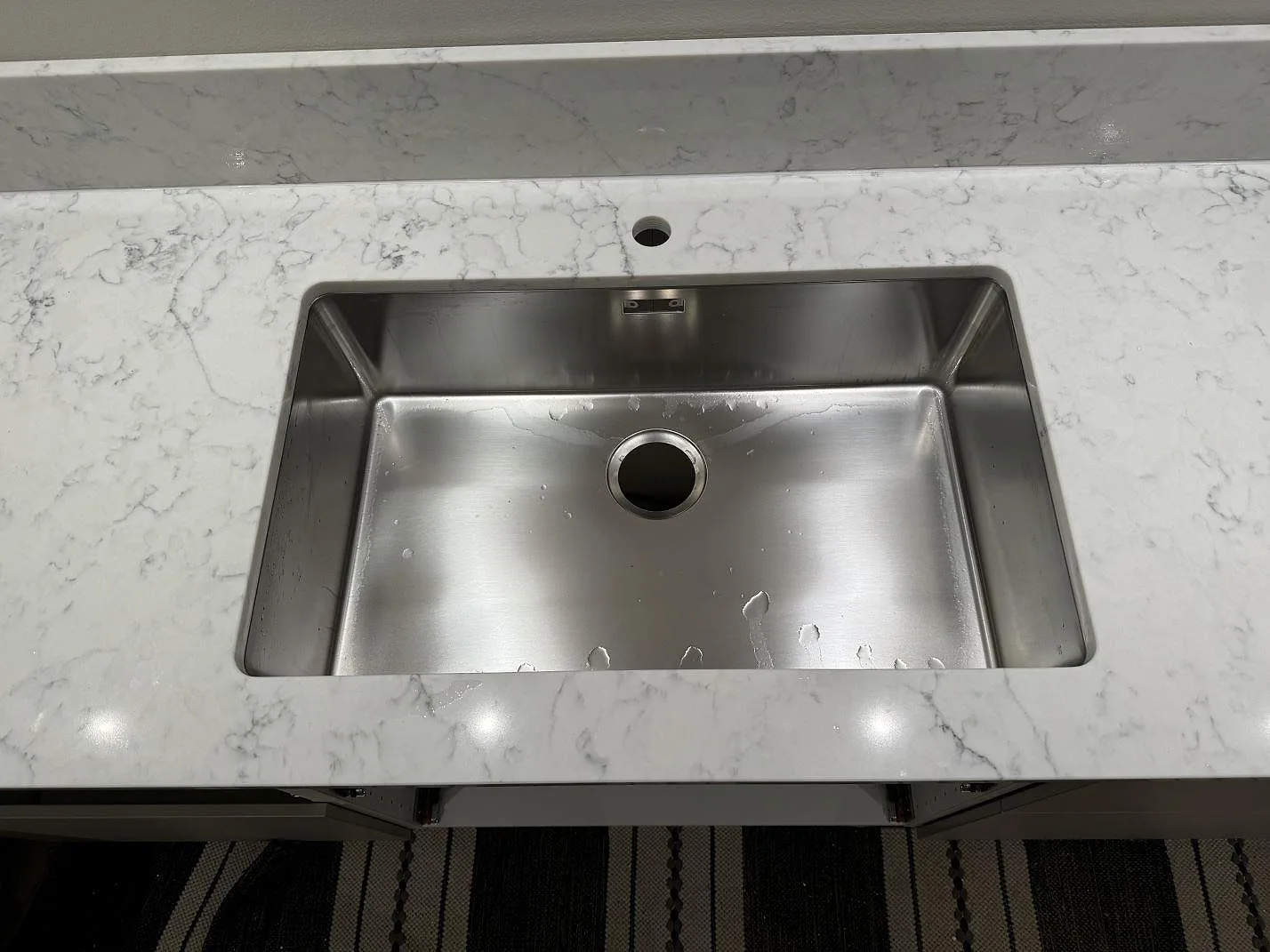 Närbild på underlimmad rostfri diskho i polerad Technistone Mystery White med uppvikt stänkkant i ett kök i Ystad.