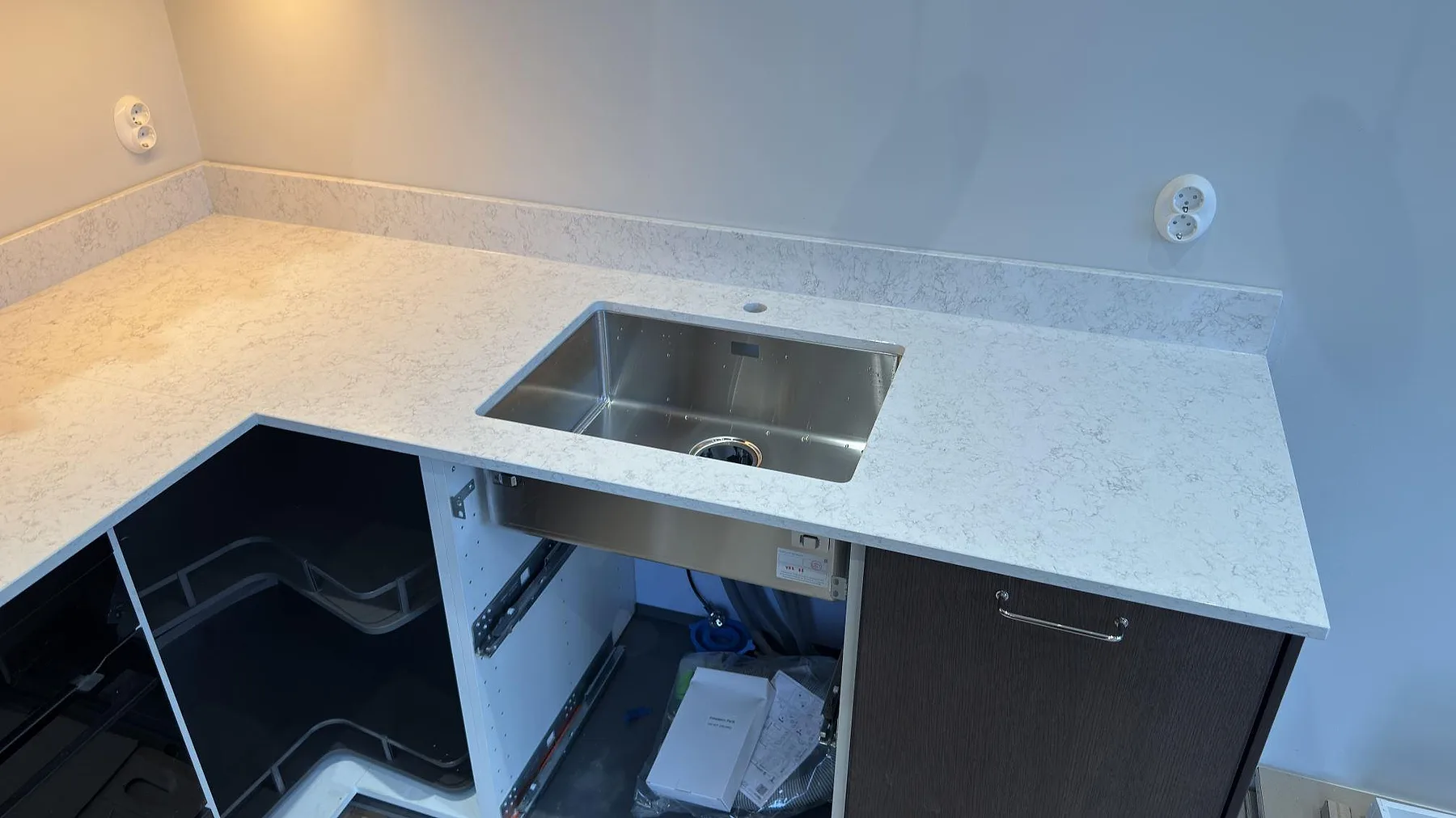 Polerad Technistone Noble Arco köksbänkskiva med underlimmad rostfri diskho och uppvikt stänkkant i ett kök i Danderyd.
