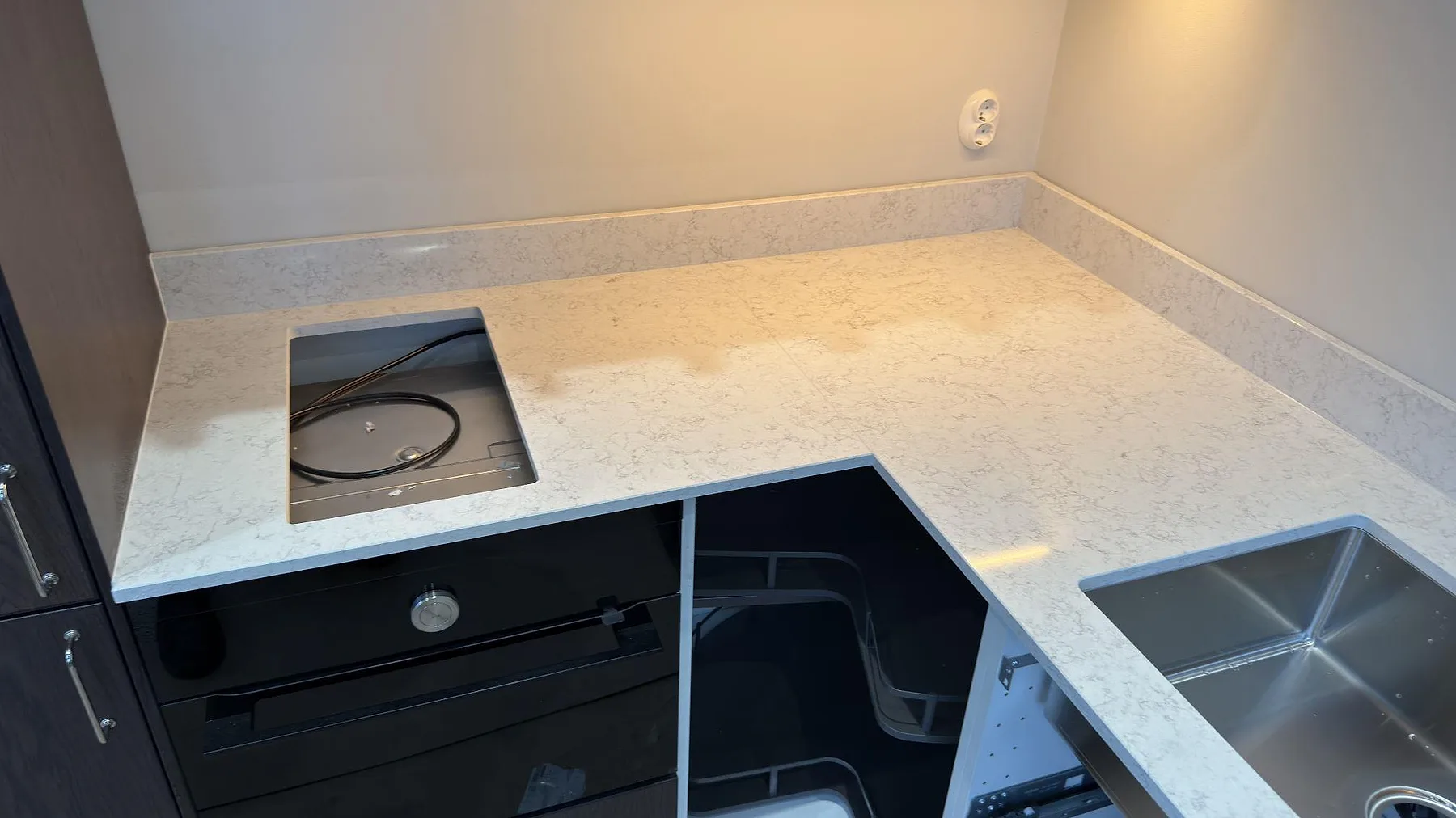 Köksbänkskiva i Technistone Noble Arco med urtag för infälld häll och underlimmad rostfri diskho, polerad komposit i Danderyd.