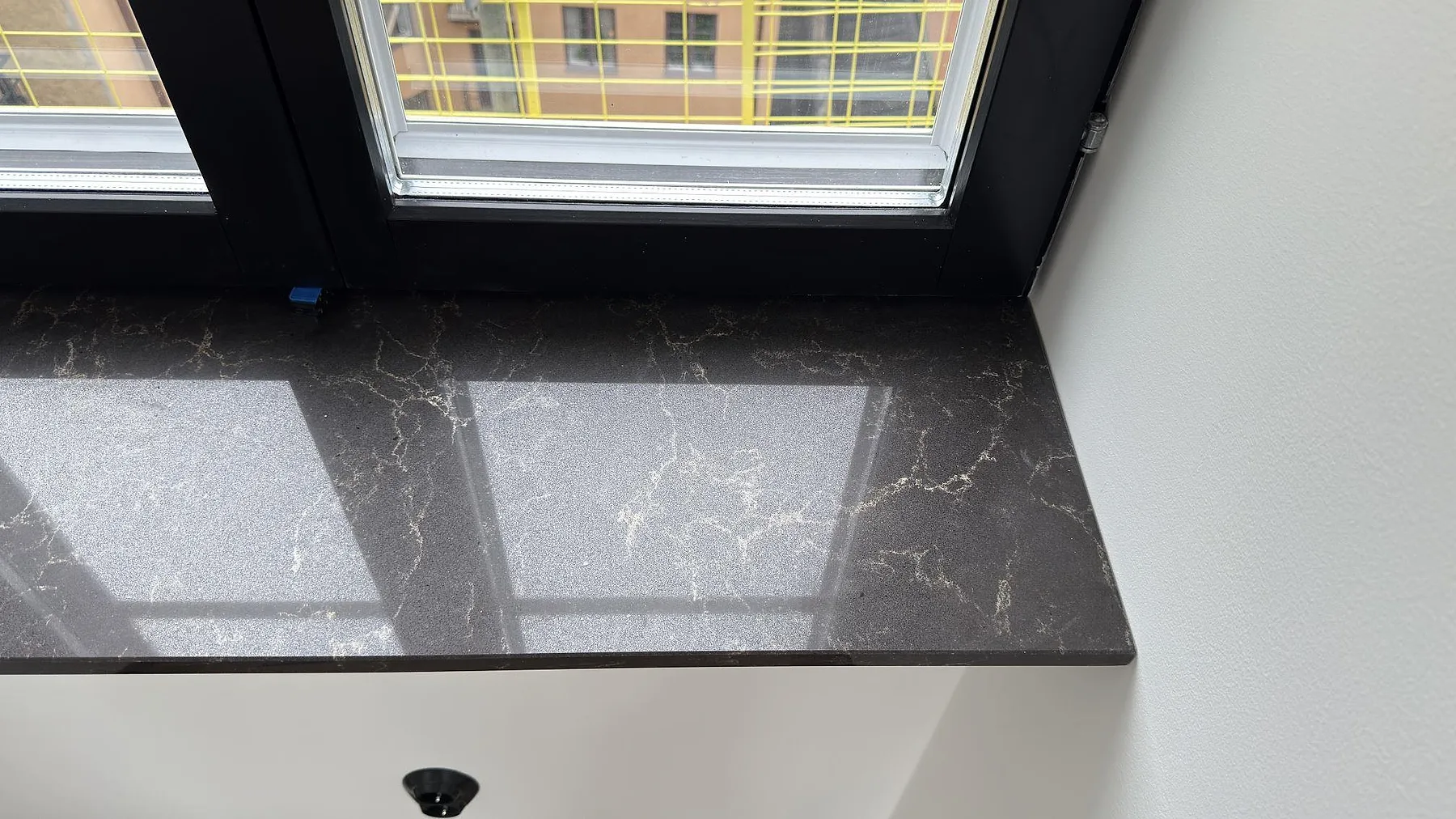Fönsterbänk i ljus Technistone Noble Arco, polerad komposit med grå ådring, i samma kök i Danderyd.