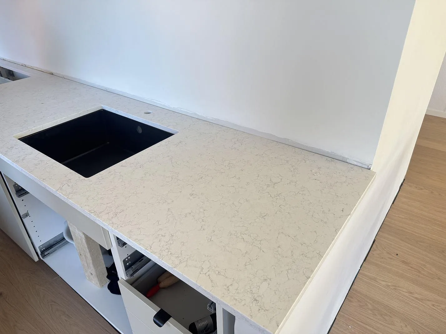 Matt köksbänkskiva i Technistone Noble Arco komposit med svart diskho och ljus grå ådring i ett kök i Lomma.