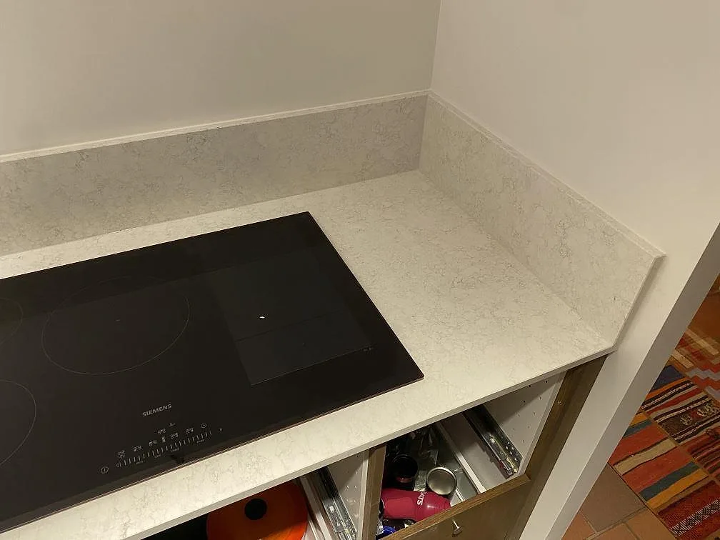 Köksbänkskiva i Technistone Noble Arco komposit, polerad, med svart häll och stänkkant vid en hörna i Malmö.