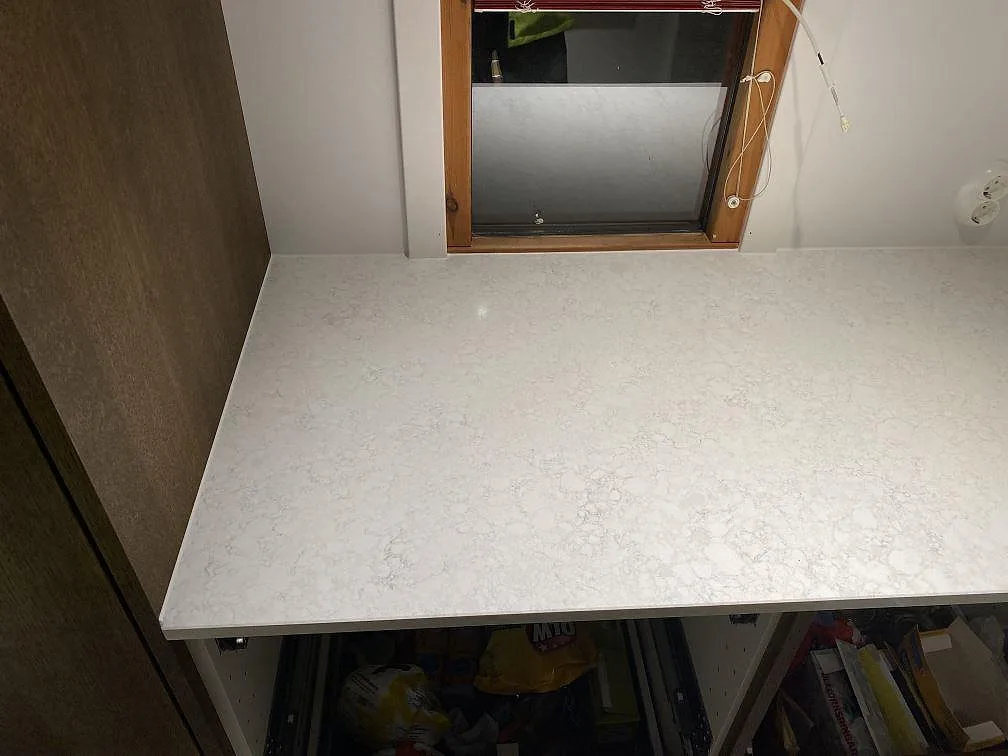 Monterad köksbänkskiva i polerad Technistone Noble Arco komposit under fönster i Malmö.