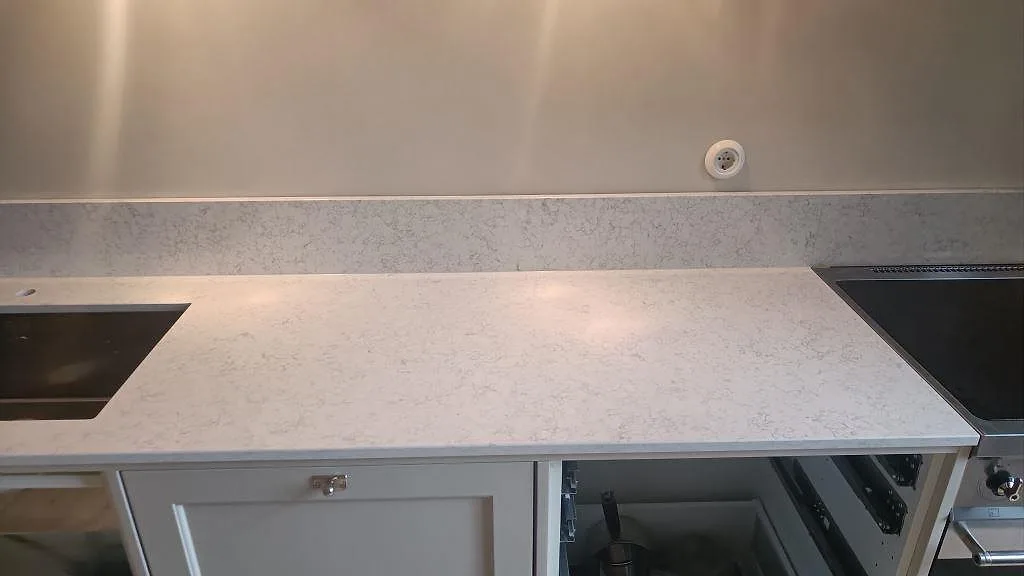 Lång arbetsyta i Technistone Noble Arco, polerad kvartskomposit med diskret grå ådring, mellan urtag och spis i Malmö.