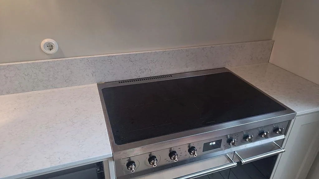 Spissida med bänkskiva i polerad Technistone Noble Arco och låg stänkkant i samma ljusa komposit i Malmö.