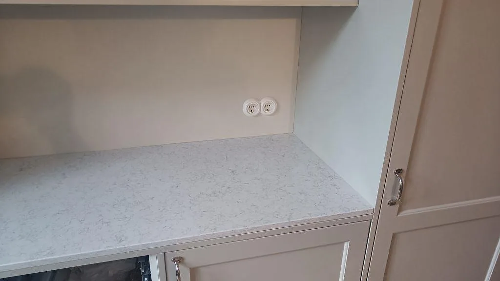 Närbild på polerad Technistone Noble Arco som köksbänkskiva under överskåp, ljus kvartskomposit med grå ådring i Malmö.