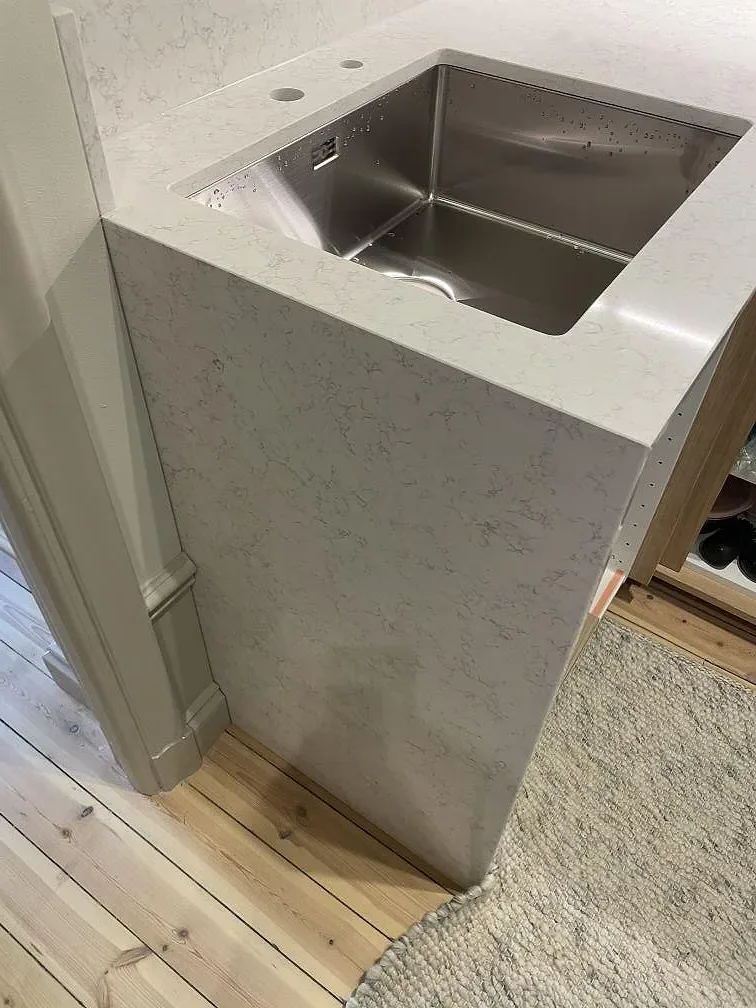 Detaljbild av Technistone Noble Arco komposit, polerad, vid diskho och sidopanel i ett kök i Stockholm.