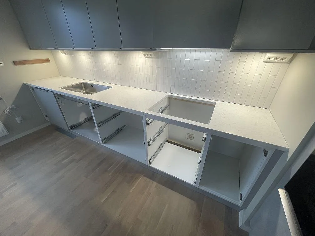 Köksbänk i vit Technistone Noble Arco under montering, med diskho och hällplats samt synlig grå ådring i ett kök i Sundbyberg.