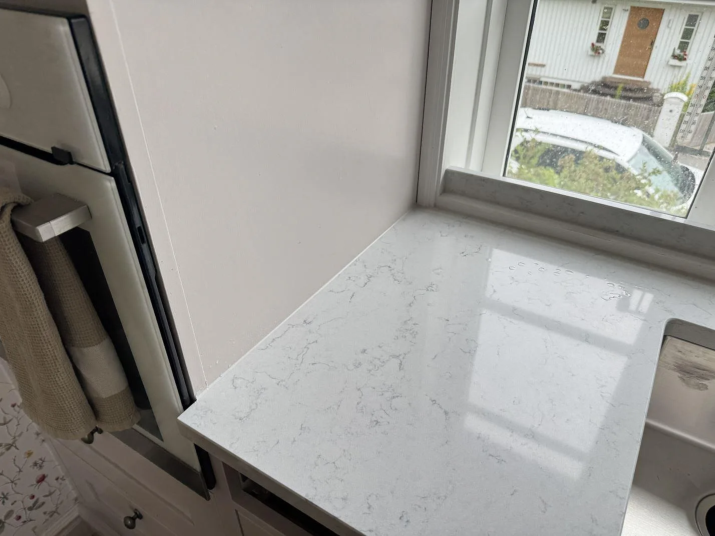 Polerad Technistone Noble Carrara vid köksfönster med ljus marmorlik ådring och blank yta i Båstad.