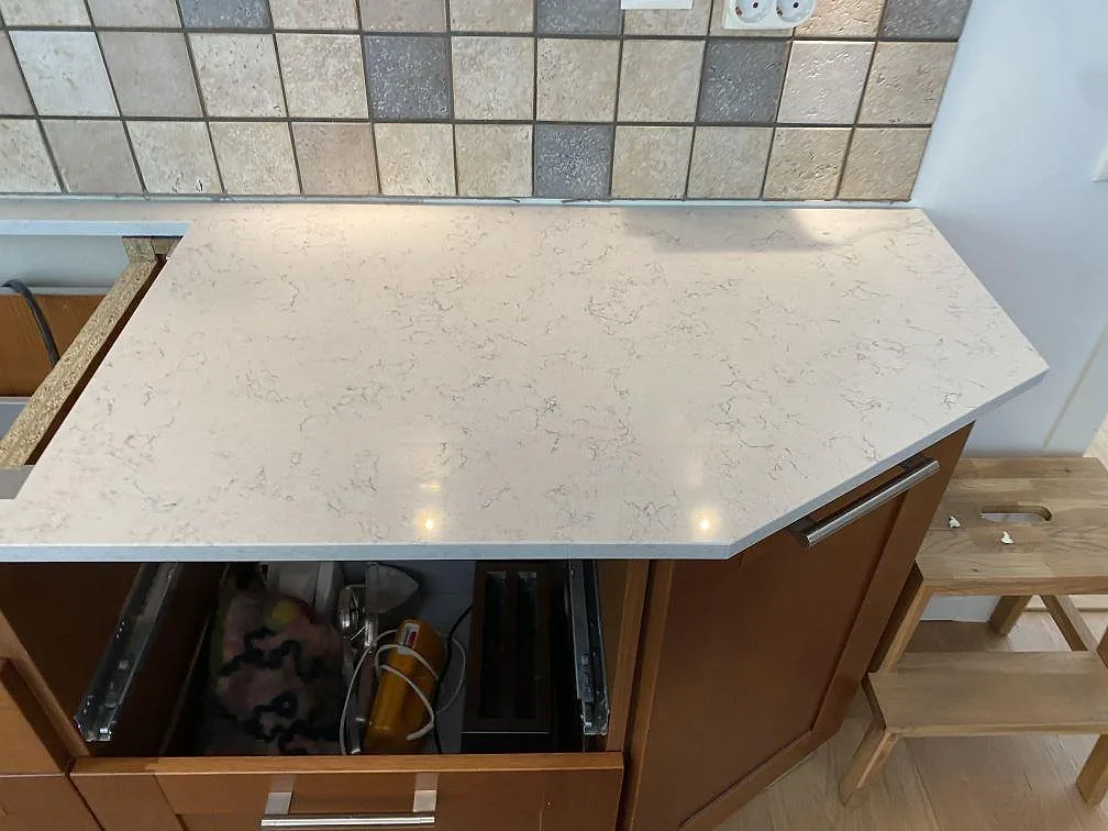 Sidobänk i polerad Technistone Noble Carrara med sned kapning och träinredning under montering i Blentarp.