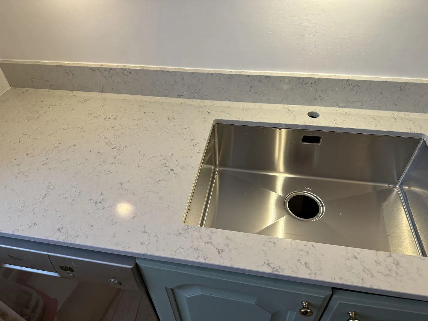Polerad Technistone Noble Carrara bänkskiva i komposit med rostfri diskho och gröngrå köksluckor i Göteborg.