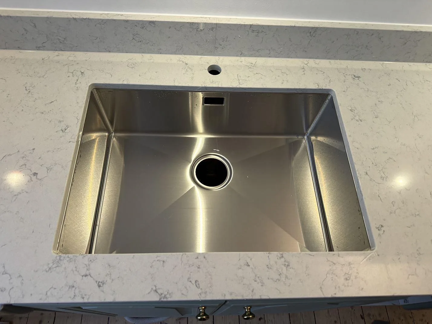 Närbild på rostfri diskho i polerad Technistone Noble Carrara köksbänkskiva med vitgrå ådring i Göteborg.