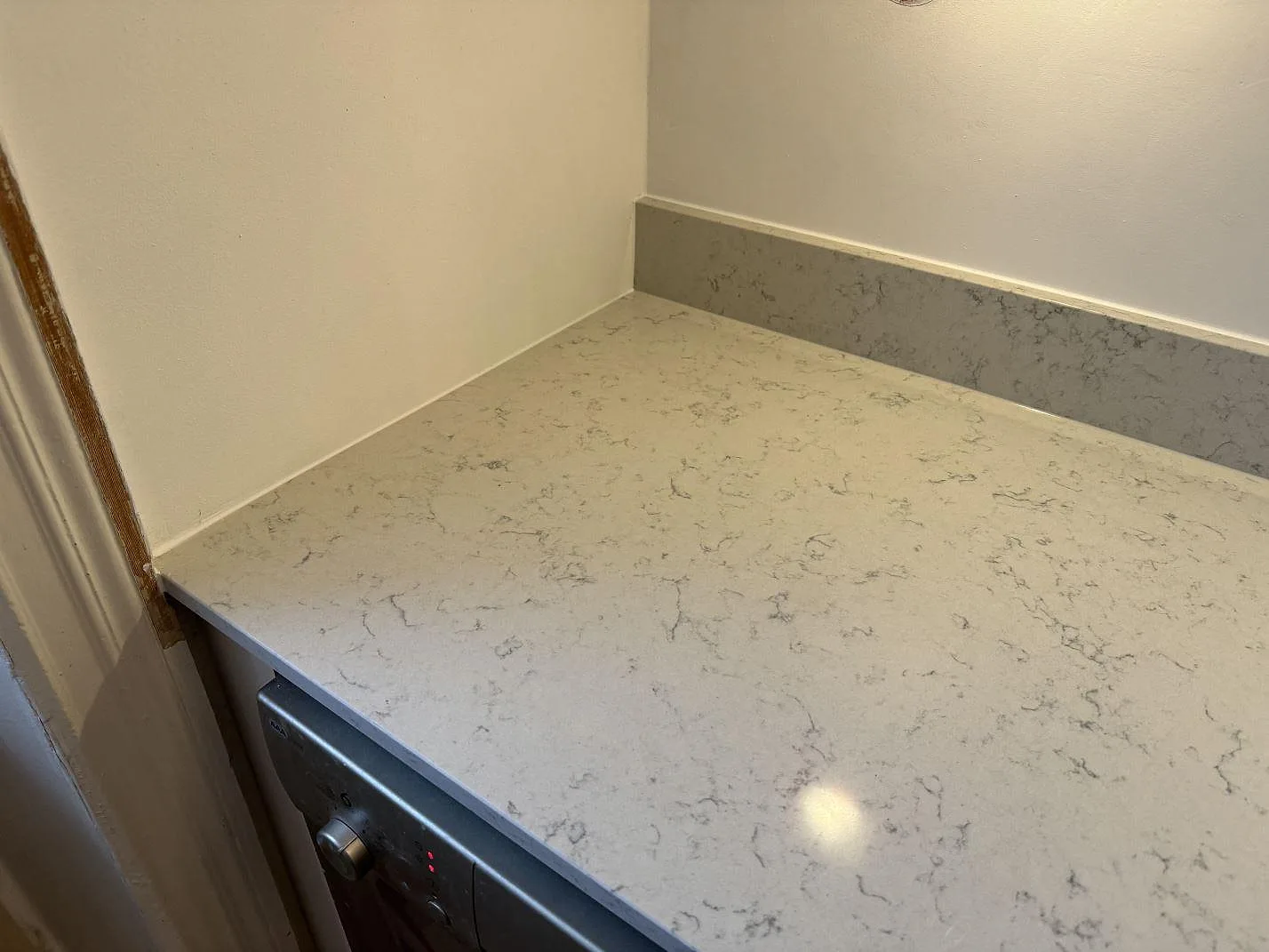 Hörn av köksbänkskiva i polerad Technistone Noble Carrara komposit med uppvikt stänkkant i Göteborg.