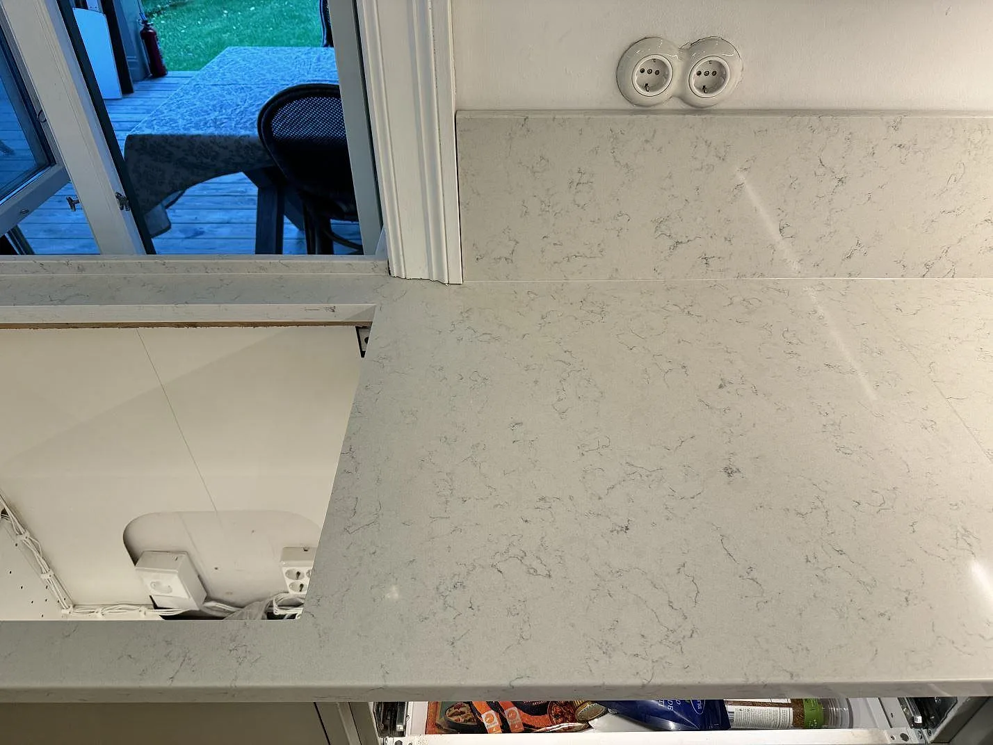 Badrumsbänkskiva i polerad Technistone Noble Carrara vid fönster, med uppvikt stenskiva och ljus grå ådring i Göteborg.
