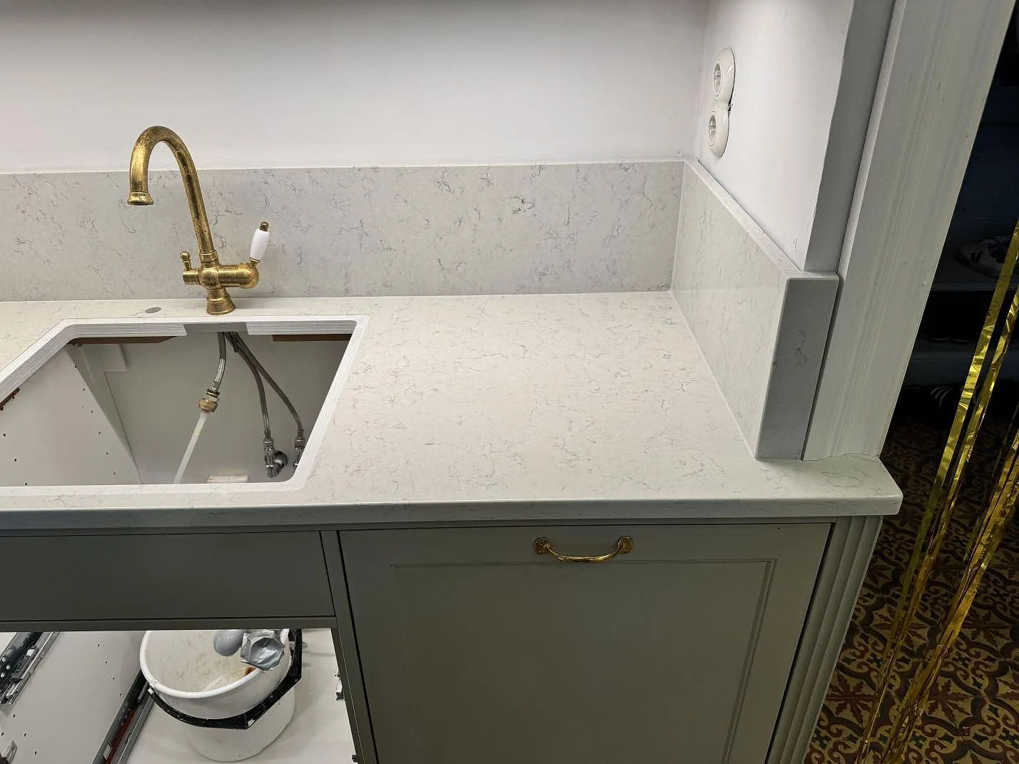 Badrumsbänkskiva i polerad Technistone Noble Carrara, ljus kompositsten, med mässingsblandare och uppvikt stänkskydd i Göteborg.