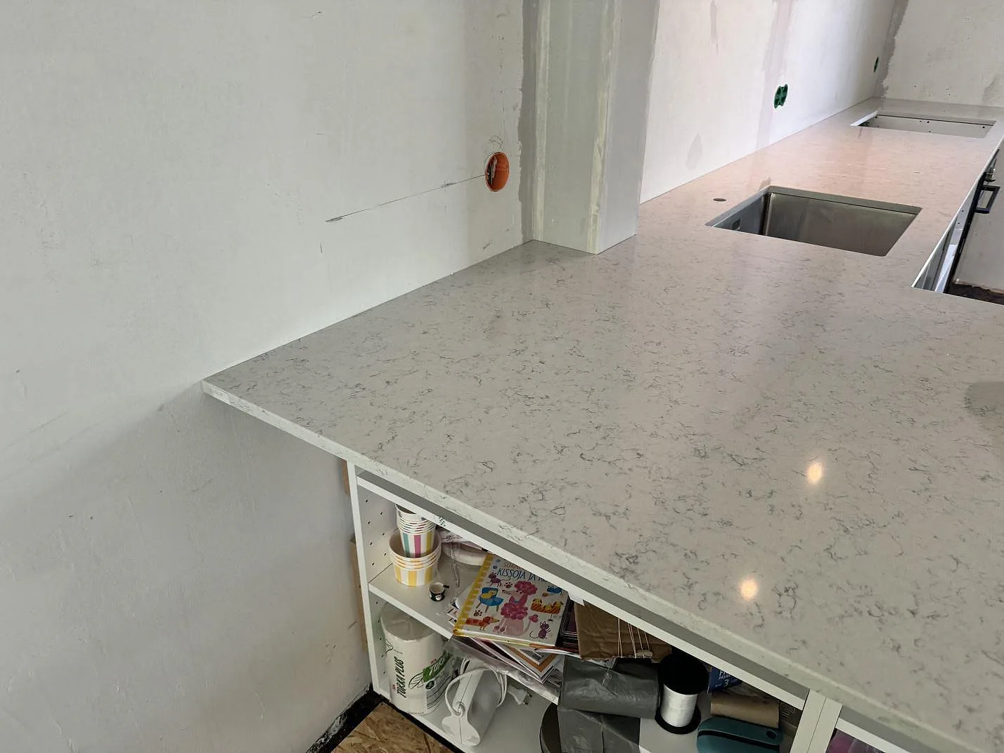 Lång arbetsyta i polerad Technistone Noble Carrara, vit kvartskomposit med grå mönstring, över öppna köksstommar i Göteborg.