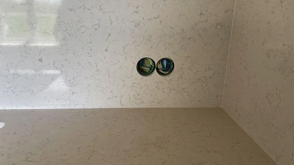 Detalj av polerad Technistone Noble Carrara komposit med bänkyta, stänkskydd och genomföringar i Hagby.