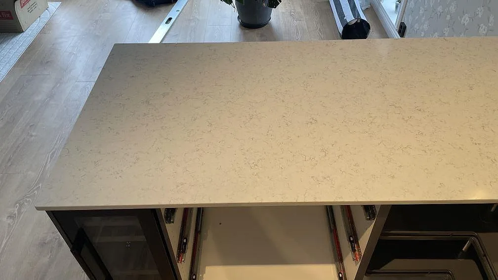 Ytnära bild av polerad Technistone Noble Carrara kvartskomposit på köksön, med ljus grund och fin grå mönstring i Jönköping.