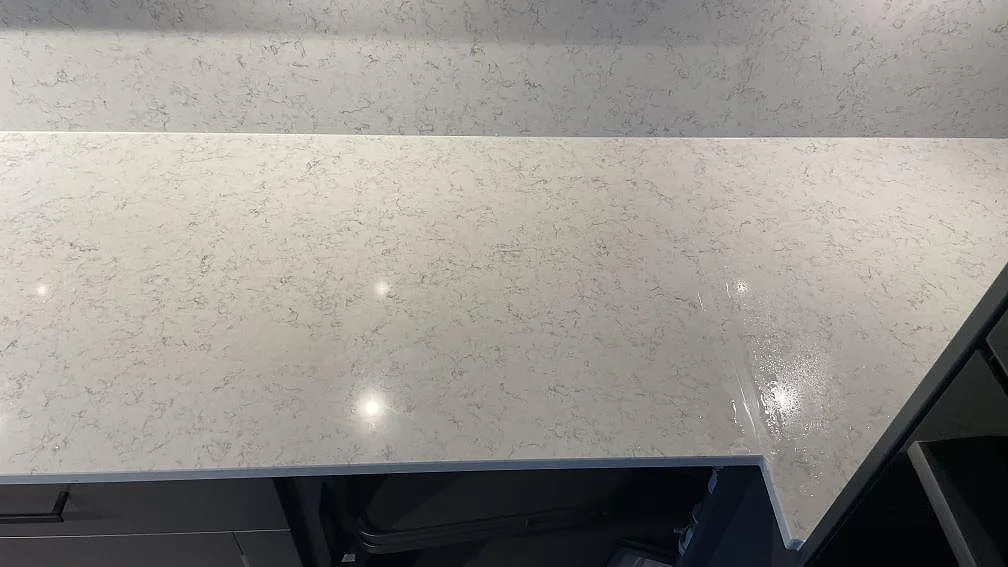 Detalj av den polerade ytan och stänkskyddet i Technistone Noble Carrara komposit på en köksbänk i Jönköping.
