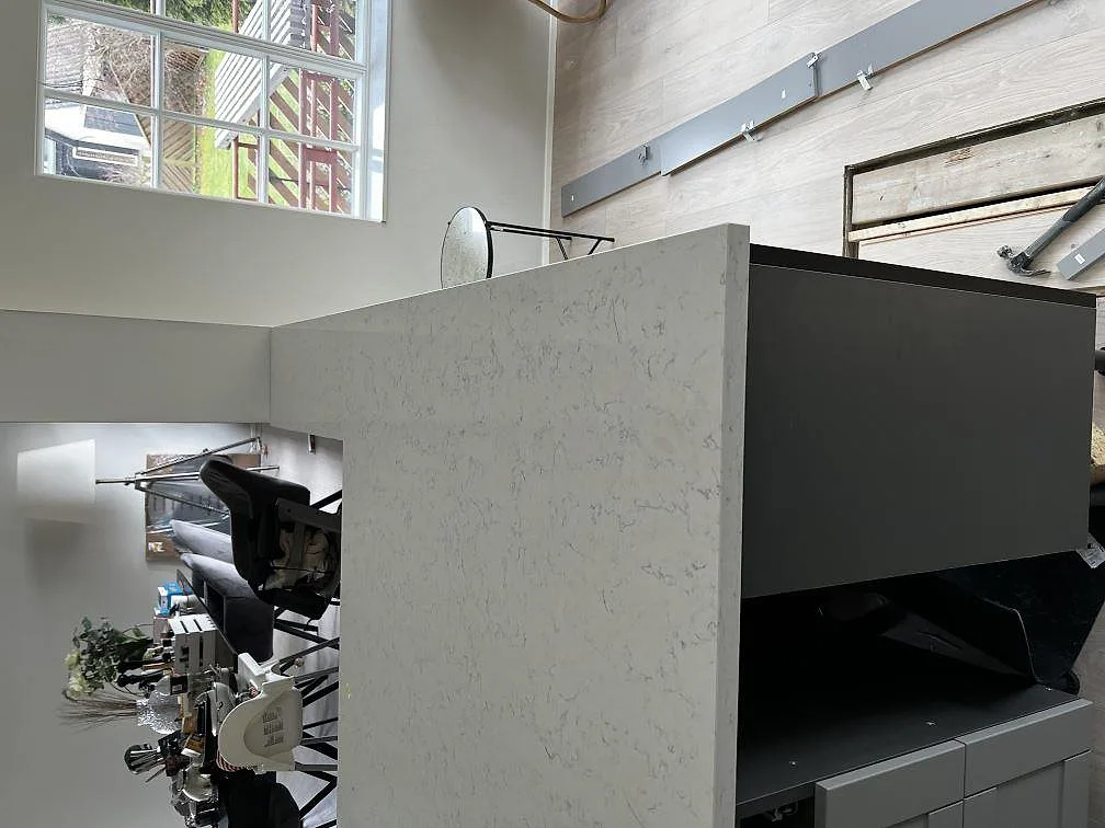 Köksbänkskiva i vit Technistone Noble Carrara, polerad, på en köksö med nedvikt sidostycke i ett kök i Kristianstad.