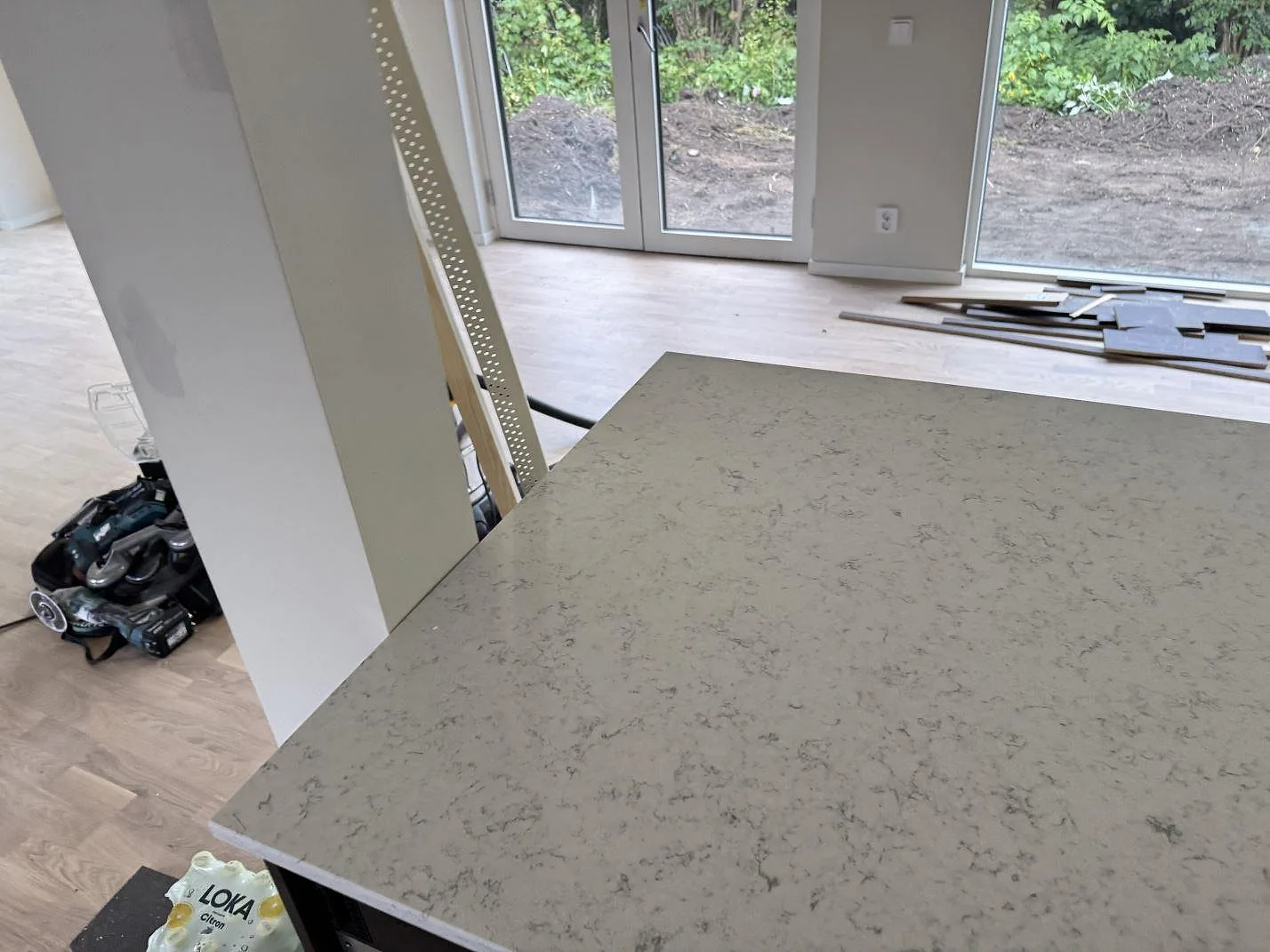 Närbild av den polerade Technistone Noble Carrara bänkskivan med ljus komposityta och grå marmorering under montering i Lomma.