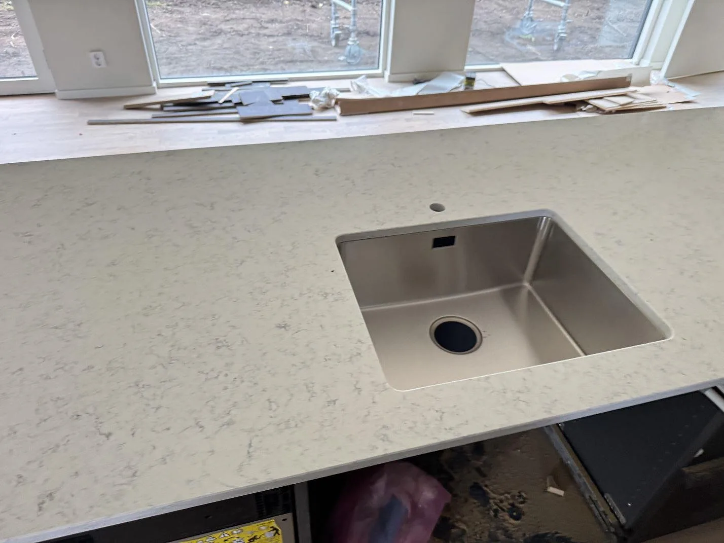Polerad köksbänkskiva i Technistone Noble Carrara med underlimmad rostfri diskho och blandarhål framför fönster i Lomma.