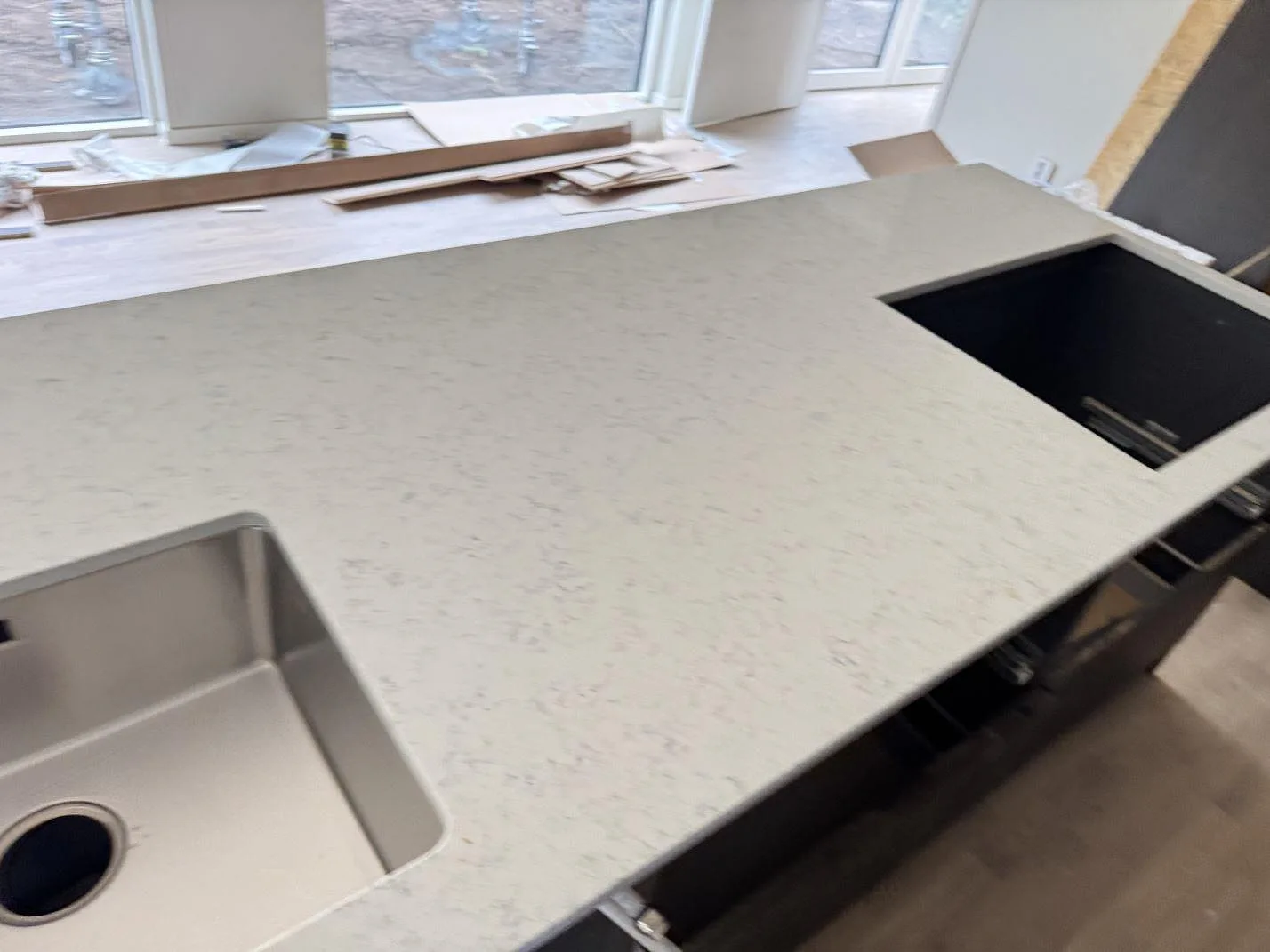 Köksbänkskiva i polerad Technistone Noble Carrara komposit med underlimmad rostfri diskho och öppning för häll i ett kök i Lomma.