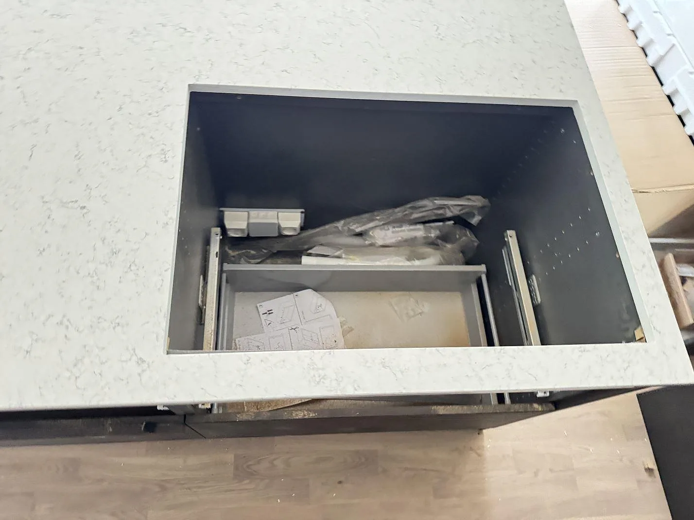 Hällöppning i polerad Technistone Noble Carrara köksbänkskiva på mörka köksstommar under montering i Lomma.