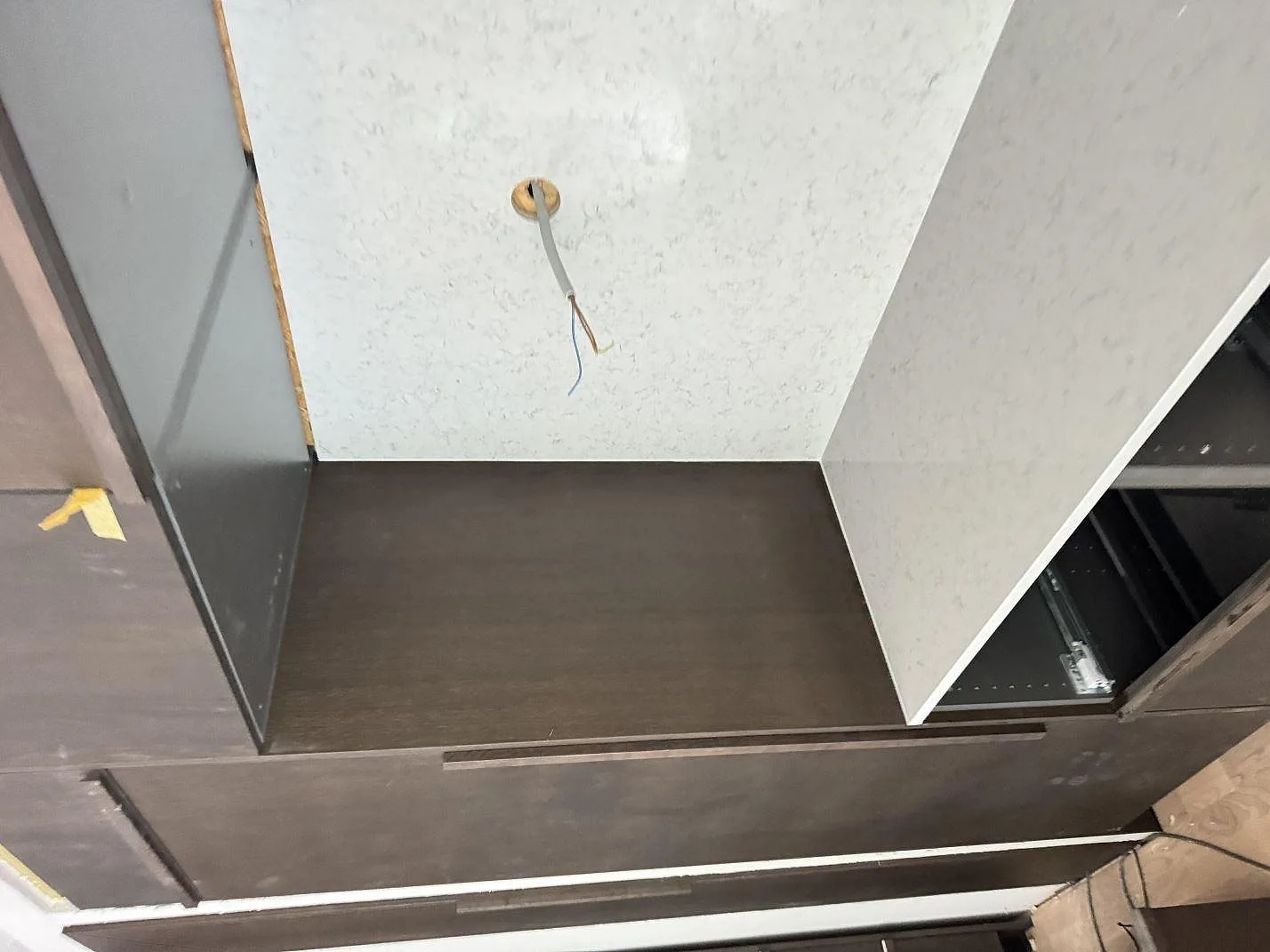 Stående stendetalj och bänkyta i polerad Technistone Noble Carrara komposit monterad vid mörka köksstommar i Lomma.