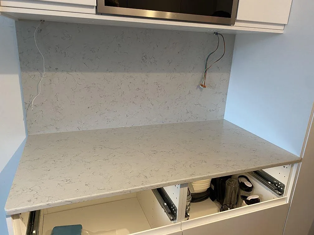Närbild ovanifrån på den polerade Noble Carrara bänkskivans ljusa yta med mjuk grå ådring i ett kök i Malmö.