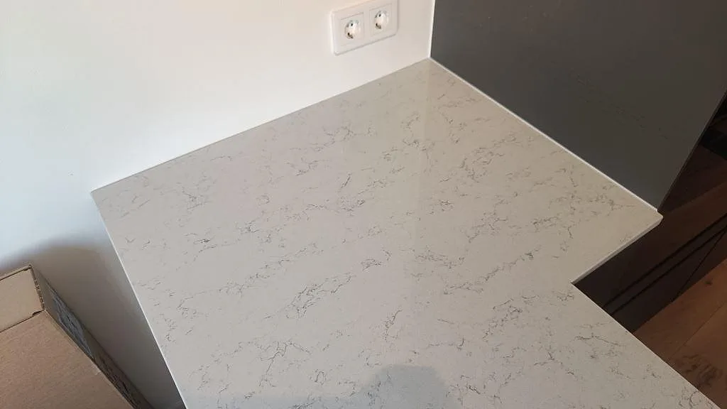 Närbild av den polerade kompositytan Technistone Noble Carrara på kökshalvön i Malmö.