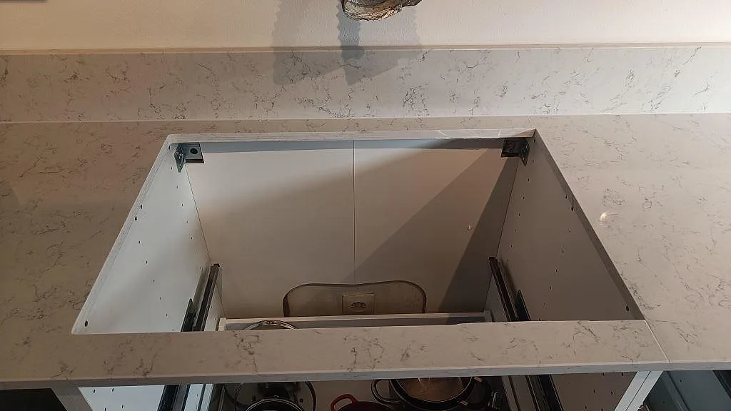 Köksbänkskiva i polerad Noble Carrara komposit med diskhons urtag och stänkkant under montering i Malmö.