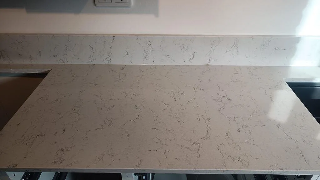Rak köksbänkskiva i vit komposit Technistone Noble Carrara med låg stänkkant och polerad yta i Malmö.