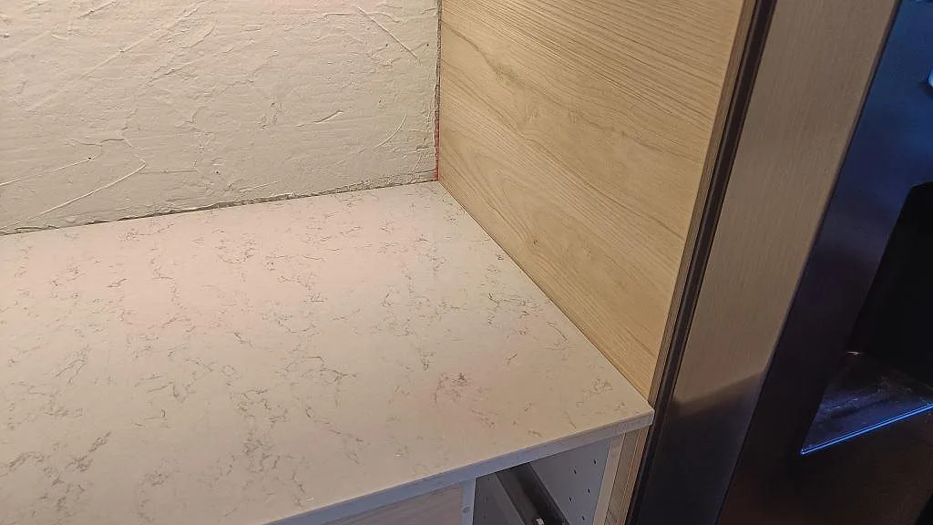 Avslut vid högskåp med Technistone Noble Carrara köksbänkskiva, ljus polerad komposit i ett kök i Malmö.