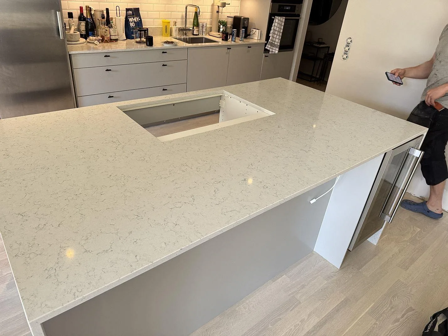 Köksö med polerad Technistone Noble Carrara komposit, vit bänkskiva med hällöppning i ett kök i Malmö.
