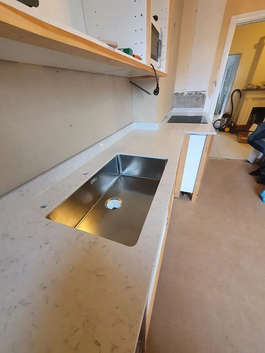 Underlimmad rostfri diskho i polerad köksbänkskiva av vit Technistone Noble Carrara med marmorlik ådring i Örebro.