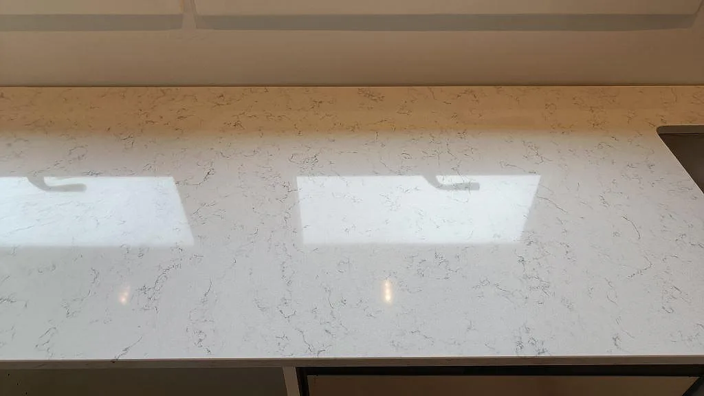 Detalj av den ljusa ådringen i polerad Technistone Noble Carrara köksbänkskiva i ett kök i Staffanstorp.