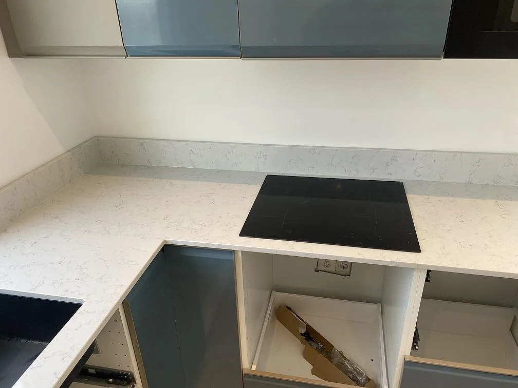 Köksbänkskiva i vit Technistone Noble Carrara, polerad, med häll och stänkkant mot vägg i Värnamo.