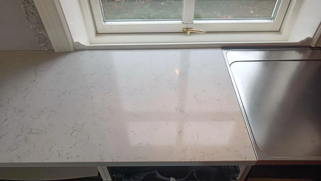 Topvy av polerad Technistone Noble Carrara bänkskiva med ljus ådring och fönsterläge i Växjö.