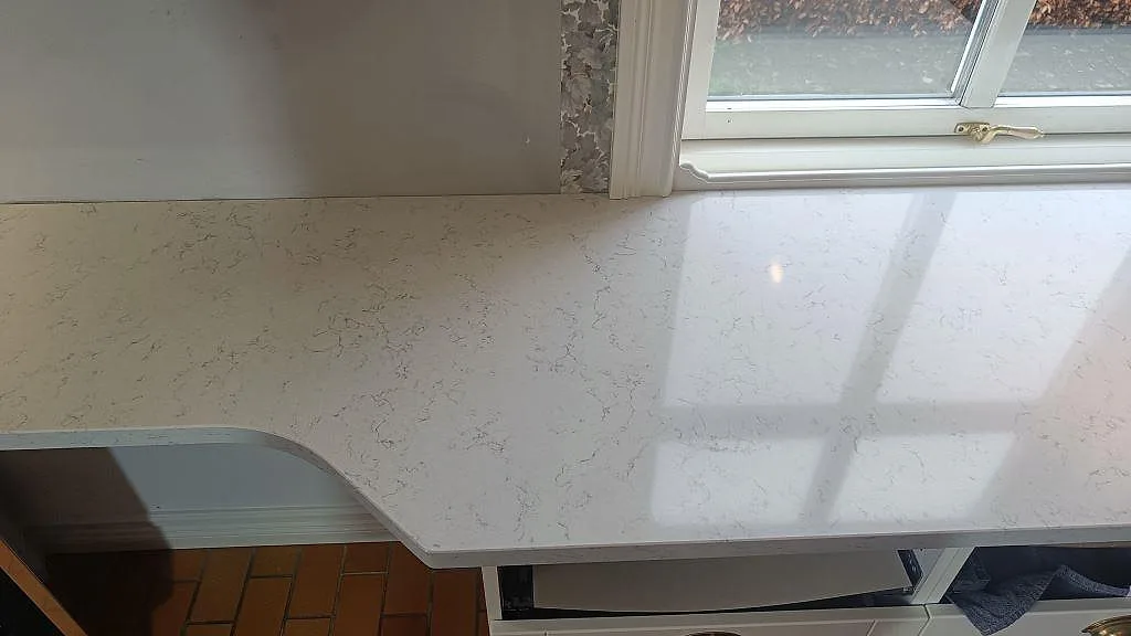 Installerad köksbänkskiva i Technistone Noble Carrara, polerad, med rundat hörn och fönster i Växjö.