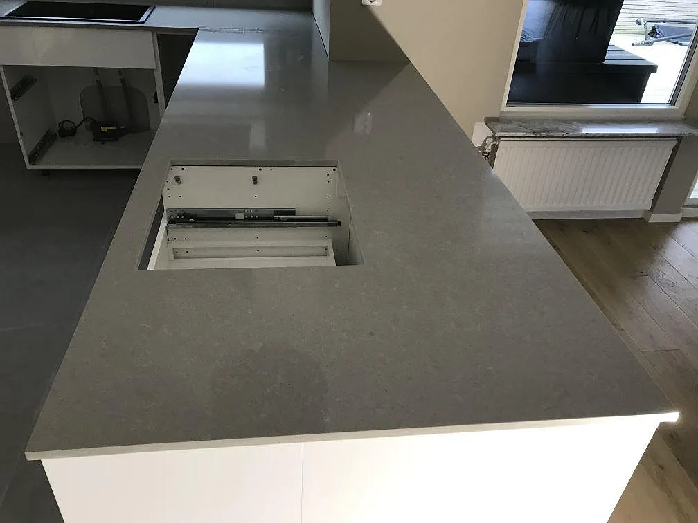Köksbänkskiva i grå Technistone Noble Concrete Grey, polerad komposit, med köksö och peninsula i ett kök i Anderslöv.