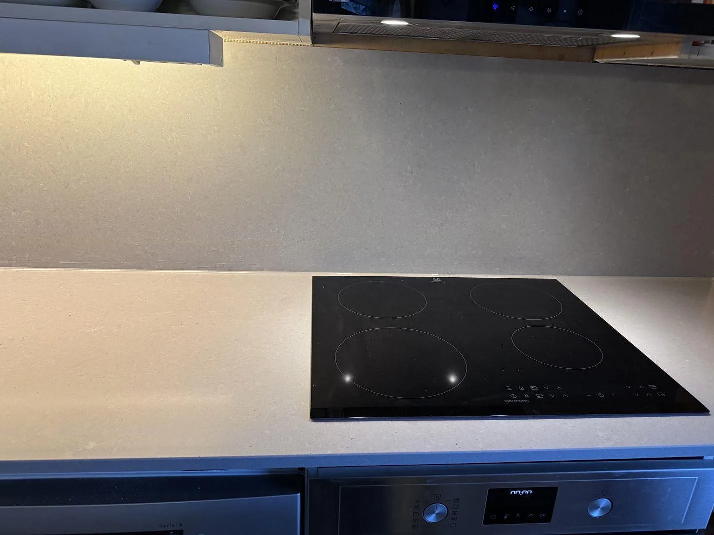 Rak köksbänkskiva i polerad Technistone Noble Concrete Grey med induktionshäll och grått stänkskydd i Båstad.