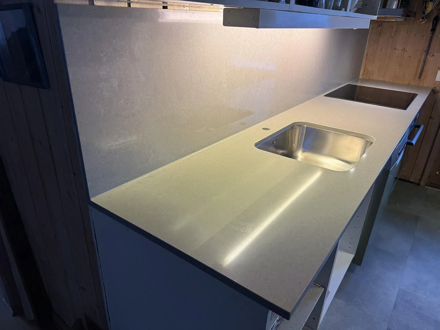 Köksbänkskiva i polerad Technistone Noble Concrete Grey, kvartskomposit, med underlimmad rostfri diskho, induktionshäll och stänkskydd i Båstad.
