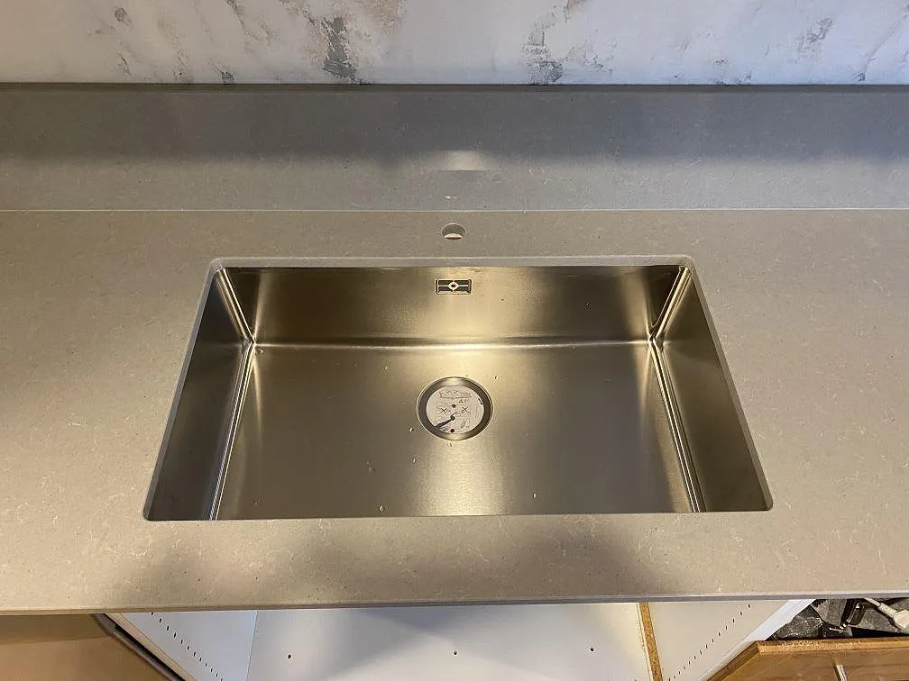 Underlimmad rostfri diskho i en polerad Technistone Noble Concrete Grey köksbänkskiva med blandarhål och låg stänkkant i Beddingestrand.