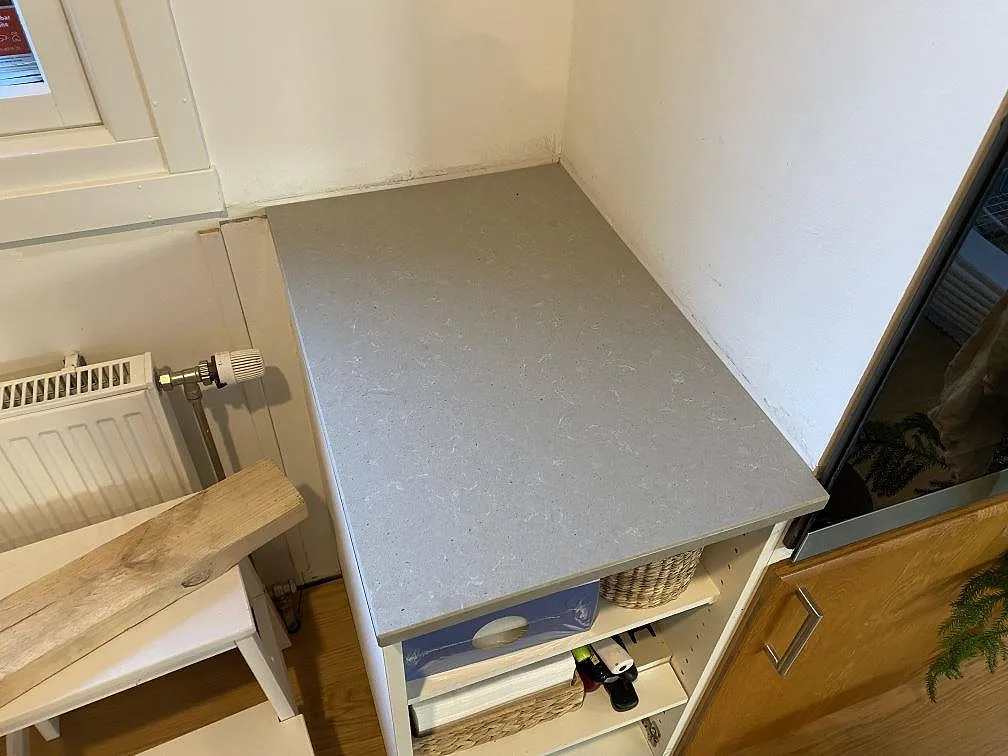 Avställningsyta i polerad Technistone Noble Concrete Grey, grå kvartskomposit, monterad intill fönster och vägg i Beddingestrand.