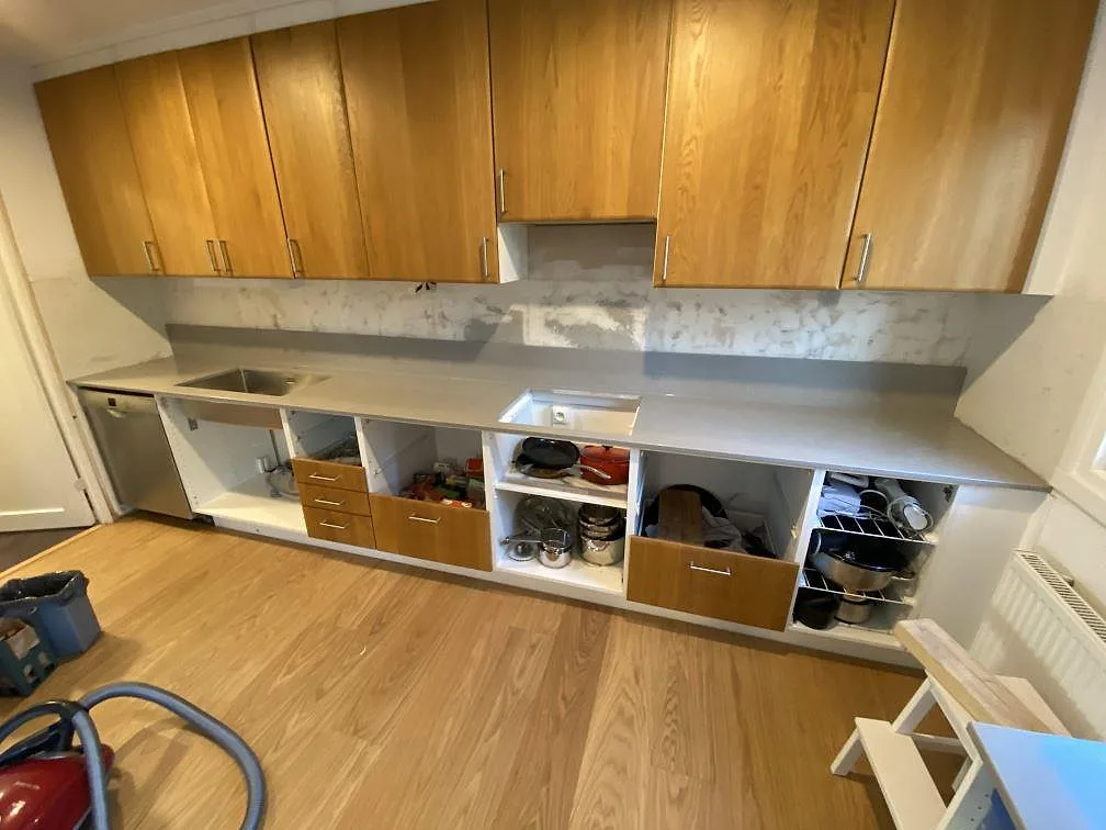 Köksbänkskiva i polerad Technistone Noble Concrete Grey, grå kvartskomposit, med underlimmad rostfri diskho och förberett hällurtag i ett kök under montering i Beddingestrand.