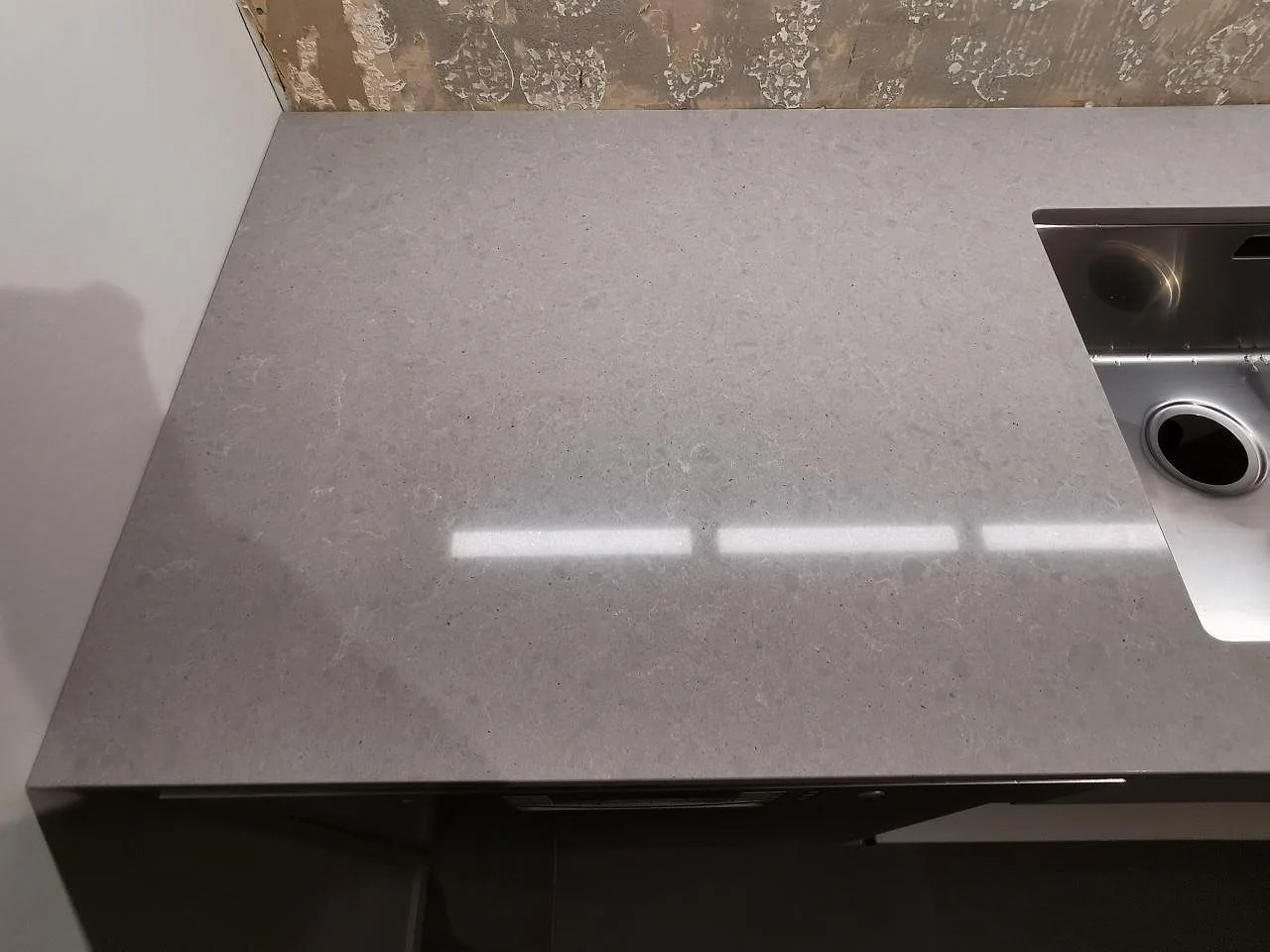 Polerad grå köksbänkskiva i Technistone Noble Concrete Grey sedd ovanifrån med rostfri diskho i ett kök i Bjärred.